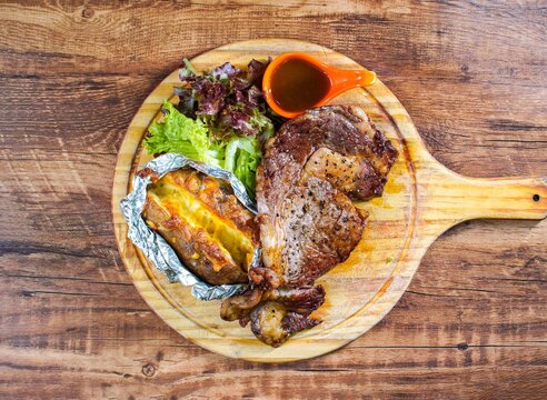Juicy grilled steak served with baked potato and fresh salad Grilled Steak With Baked Potato