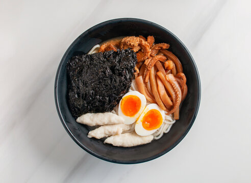 Soft noodles served with egg seafood and seaweed in a flavorful broth