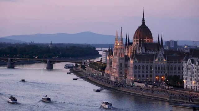 budapest parliament danube river night cityscape lights, tourists and boats move along the danube river at evening in budapest hungary featuring illuminated parliament building and city skyline
