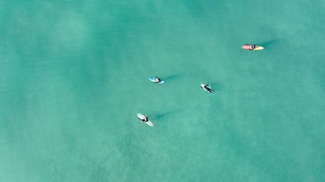 Aerial view of surfers waiting for waves in the turquoise ocean water at Perranporth, Cornwall, United Kingdom.