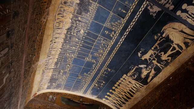 Astronomical ceiling inside KV17 tomb of Seti I, Valley of the Kings, Luxor, Egypt, featuring golden star calendar, zodiac constellations and celestial figures on deep blue background.
