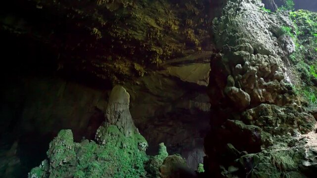 Cinematic view of the Bat Cave (Hang Doi) in Pu Luong Nature Reserve, Vietnam, featuring ancient limestone karst formations and lush green wilderness.