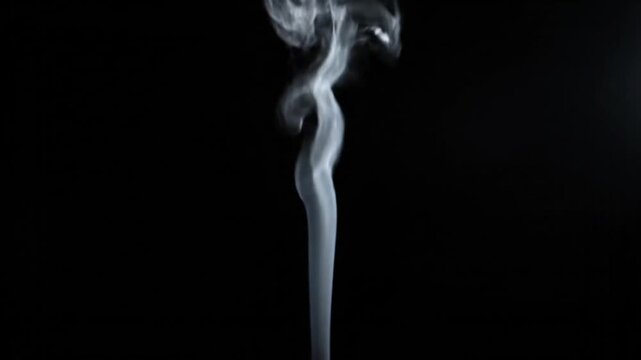 A thin trail of white smoke rises against a black background