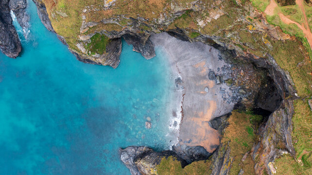 Aerial view of the rugged cliffs and turquoise waters of Hell's Mouth cove with a secluded beach in Camborne, Cornwall, United Kingdom.