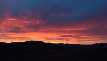 Obraz premium Vibrant sunset over mountain silhouette and valley