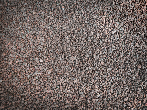 Top view full frame background texture of dark crushed stones and industrial construction gravel.