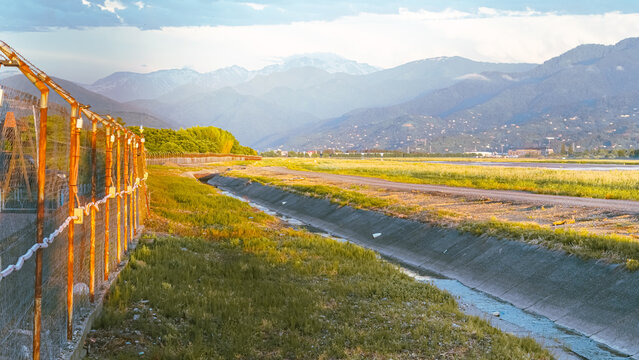 Scenic landscape with a ditch next to a wire fence and distant misty mountains