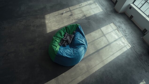 Overhead image showing a distorted bean bag laid on flat concrete flooring in a vacant room