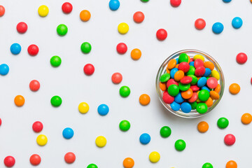 Multicolored candies in a bowl on a colored background. birthday and holiday concept. Top view with...