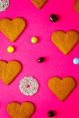 Fototapeta premium Top view of candies and heart shaped cookies on a vibrant pink background. Dessert photography, sweet treats.