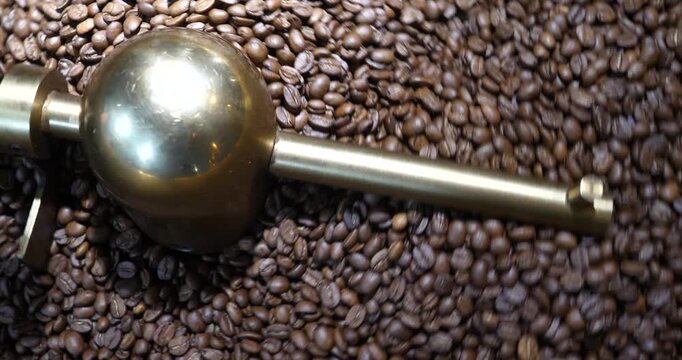 Roasting process in coffee roasting machine,Natural roast coffee beans mixing,mixing machine mixes roasted coffee beans in roaster, close up