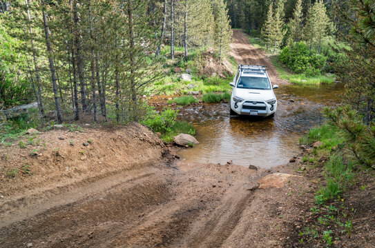 Red Feather Lakes, CO, USA - June 3, 2016: Toyota 4Runner SUV crossing a mountain stream (Sand Creek Road) in Colorado's Rocky Mountains