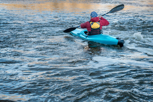 male kayaker is paddling turbulent river with a fast flow