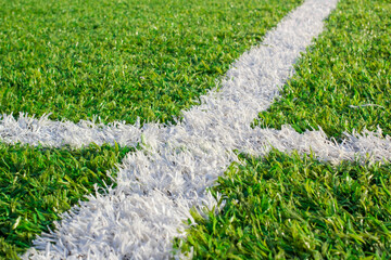 White painted boundary lines crossing on synthetic green soccer turf with playing field grass field sports field marking stadium turf artificial grass  © stockpixelstudio