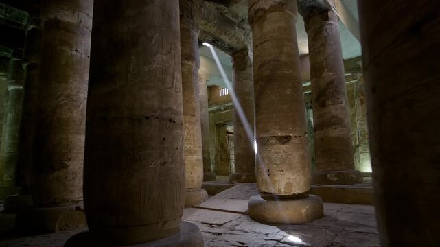 Sacred hypostyle hall at Abydos temple of Seti I, Egypt, ancient columns with carved hieroglyphics and gods receding in atmospheric perspective toward illuminated sanctuary.