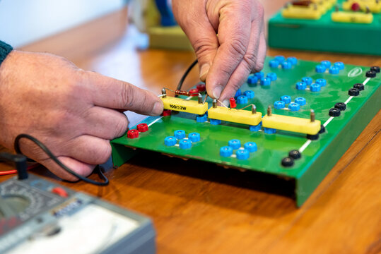 Technician Hands Assembling Electronic Circuit Components on Training Breadboard in Electronics Workshop