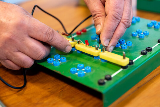Technician Hands Assembling Electronic Circuit Components on Training Breadboard in Electronics Workshop