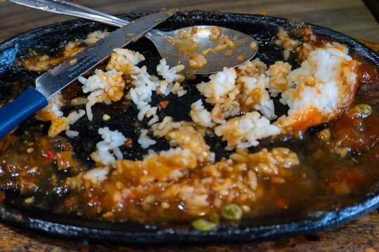 Leftover Rice And Sauce On A Cast Iron Plate With Cutlery