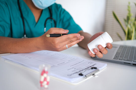 A doctor holds a bottle of pills, explains the prescription, how to use it, or the dosage to a patient, recommends quality medications, and demonstrates the concept of healthcare and treatment.
