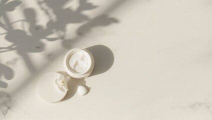 Fototapeta premium Open cosmetic jar with cream plus lid and small dollop on a bright surface with shadows