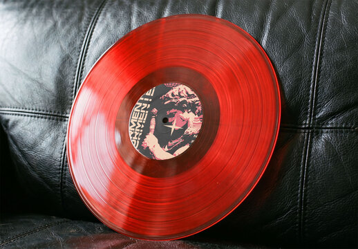 Mockup of Spindle Hole label in Red Vinyl Record Rests on a Black Leather Couch