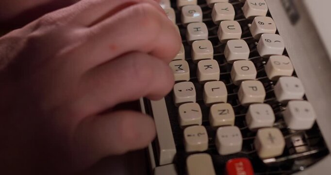 Close up of a man typing with a vintage typewriter