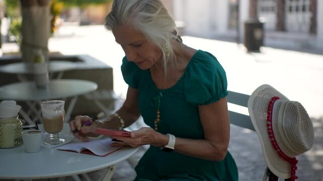 Mature woman tourist writing in her journal at a cafe in Loreto, sipping coffee and enjoying her time while planning her day in Baja California Sur, Mexico.