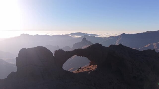 Breathtaking aerial view of the Arco del Aserrador, a stunning natural stone arch. Majestic mountain landscape of Gran Canaria at sunrise