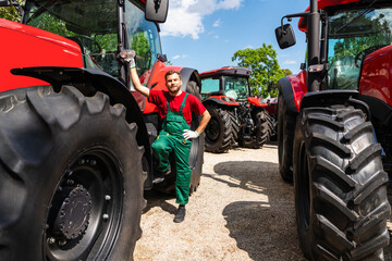 Adult male mechanic standing near tractor at farm equipment dealership © Barillo Images