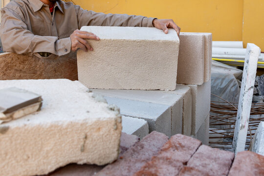 Construction Worker Hands Stacking Autoclaved Aerated Concrete AAC Blocks on Site