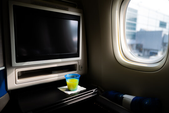 A business class seat and drink on an airplane