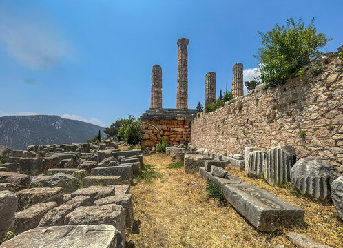Delphi, Greece - July 23, 2024: Temple of Apollo park and ruins. Fields of stones and a few columns sticking in the blue sky