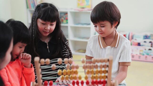 Teacher teaching children math with an abacus in kindergarten class. Asian kids learning and playing with educational toys in preschool daycare room, early childhood development.