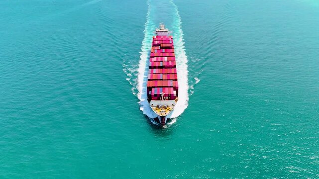 Big pink container ship sails toward its destination, viewed from aerial top above. Cargo transportation concept