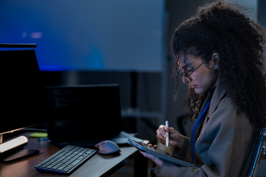 South Asian male and Black female software developers pair-program at dual monitors displaying network security algorithms at night.