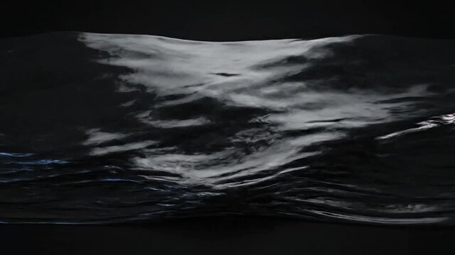 A dark liquid surface ripples with soft light and deep shadows