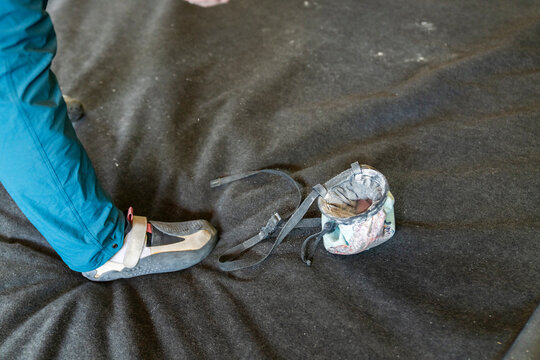 climber with chalk bag on bouldering pad inside gym