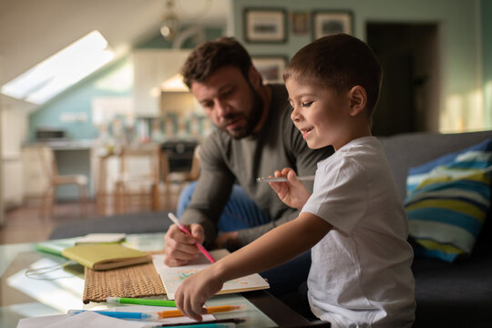 Cheerful boy choosing marker pens while drawing with father