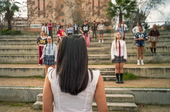 Young woman facing a group of students on outdoor bleachers