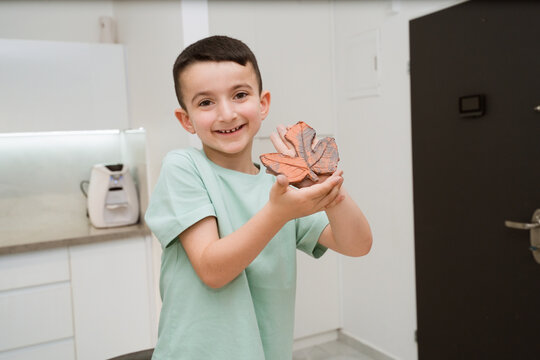 Child enjoys working with clay creating textured leaf shape in kitchen