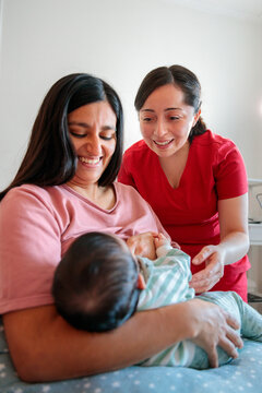 Mother and midwife smiling at baby