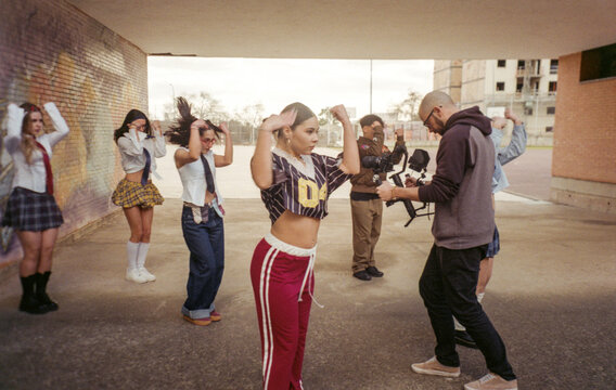 Filmmaker filming a group of young people dancing outdoors