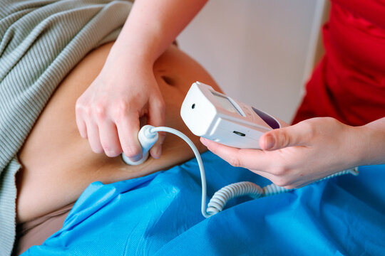 Closeup of midwife using fetal doppler on pregnant abdomen