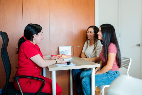 Midwife counseling teenage girl and mother in clinic