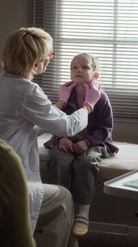 Vertical video of Caucasian female pediatrician palpating neck of Caucasian child patient during medical checkup. Clip is ideal for healthcare services and pediatric clinic advertising