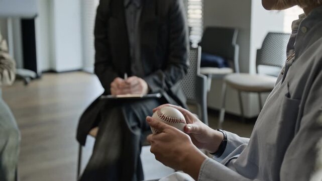 Tilt up shot of girl with glasses holding baseball and speaking during group therapy session with female psychotherapist. Video for mental health campaigns and support group promotions