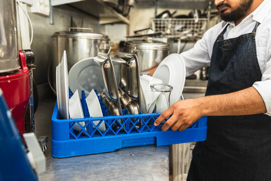 Kitchen worker carrying crate of clean dishes