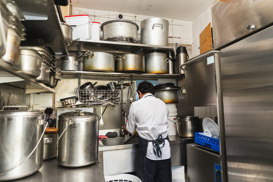 Worker at dishwashing station in commercial kitchen