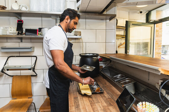 Chef plating traditional Indian dosa on metal tray