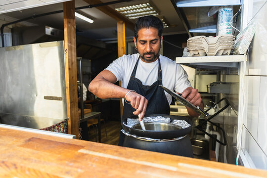 Cook stirring a large pot in commercial kitchen